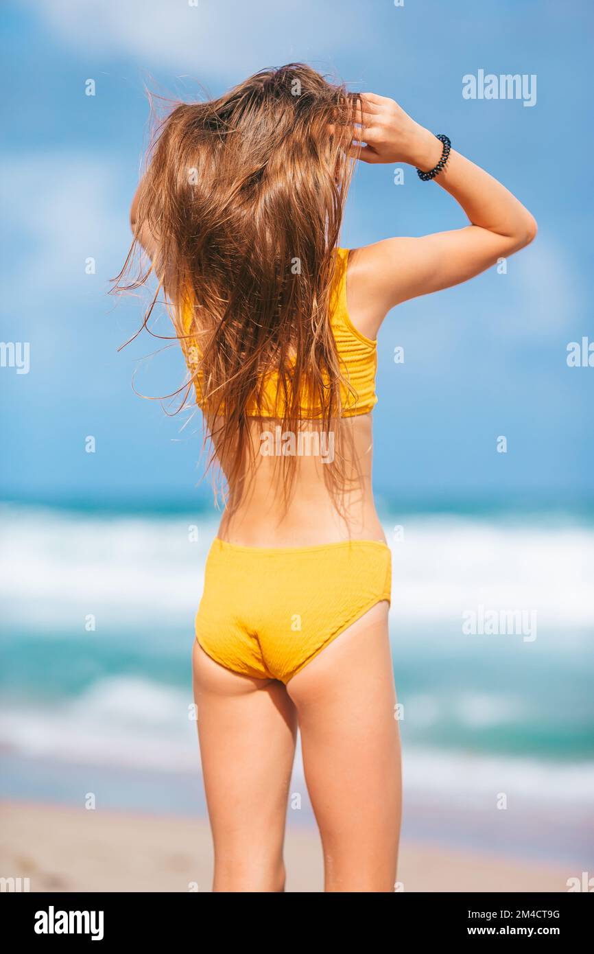 Bezauberndes, schlankes Mädchen in gelbem Badeanzug mit einer perfekten Figur am Strand Stockfoto