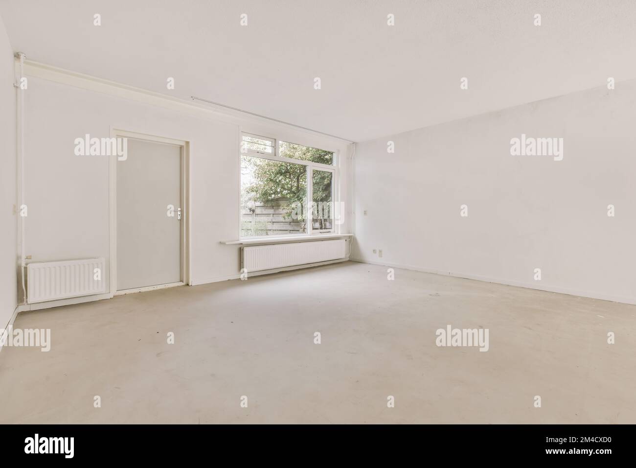 Ein leeres Wohnzimmer mit weißen Wänden und Fußboden auf der rechten Seite ist ein großes Fenster mit Blick auf die Straße Stockfoto