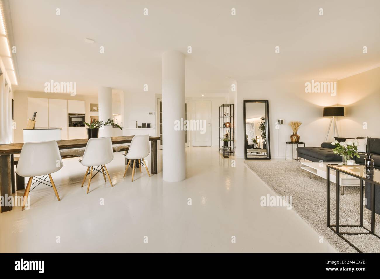 Ein Wohn- und Essbereich in einem Haus mit weißen Wänden, Fußboden und großen Fenstern mit Blick auf die Straße Stockfoto