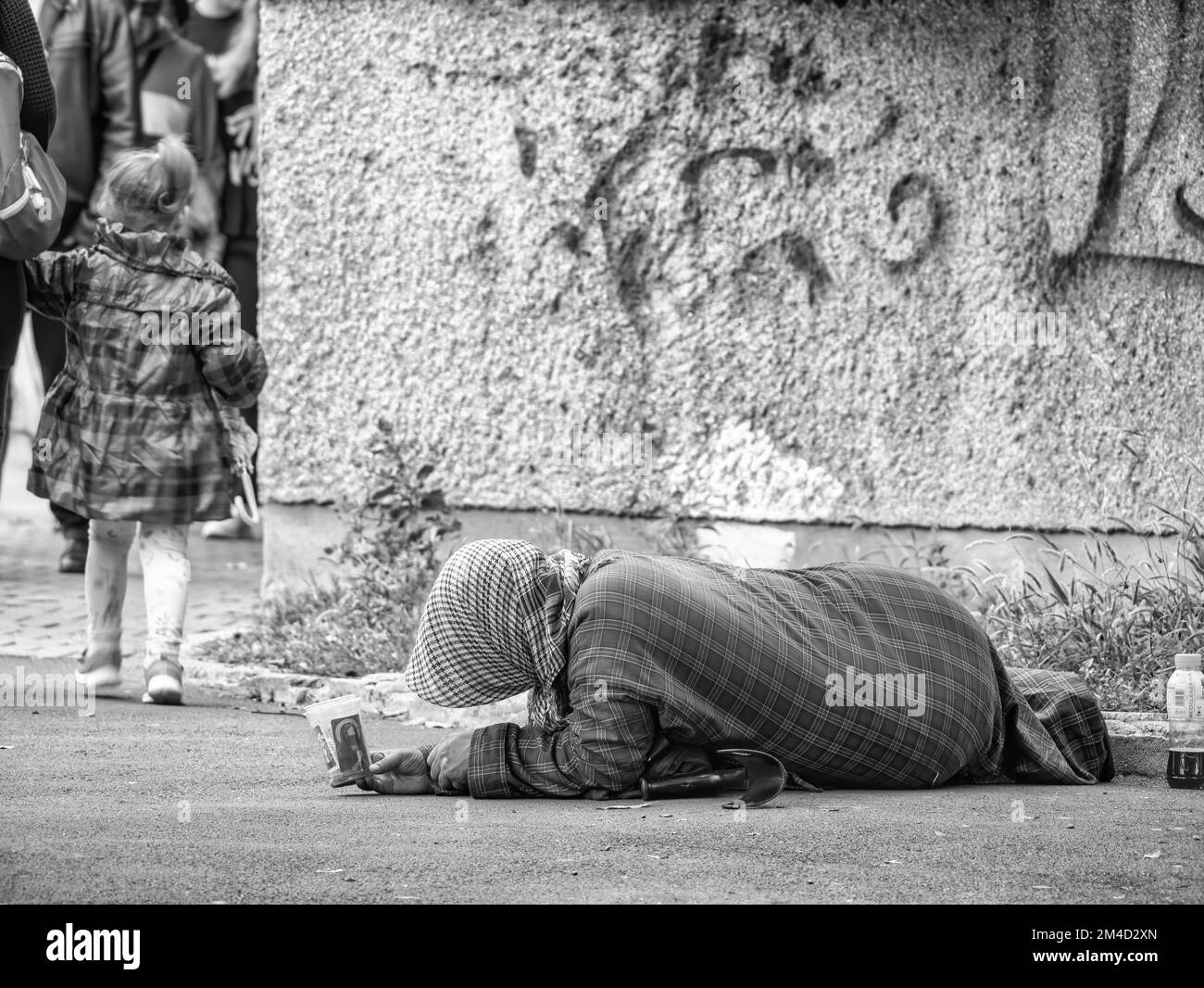 Alte ältere arme Frau mit dem Gesicht nach unten auf dem Seitenweg. Bettler im Zentrum von Bukarest, Rumänien Stockfoto