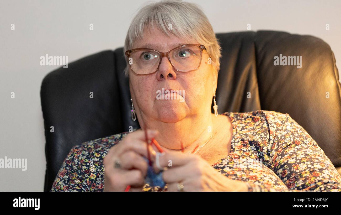 Ältere Dame strickt und sieht gleichzeitig fern Stockfoto