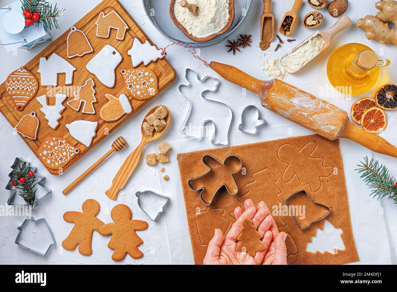Weihnachtliches Lebkuchen in unterschiedlicher Form mit Zutaten für Lebkuchen und den Händen einer Bäckerin, Draufsicht, flach liegend Stockfoto