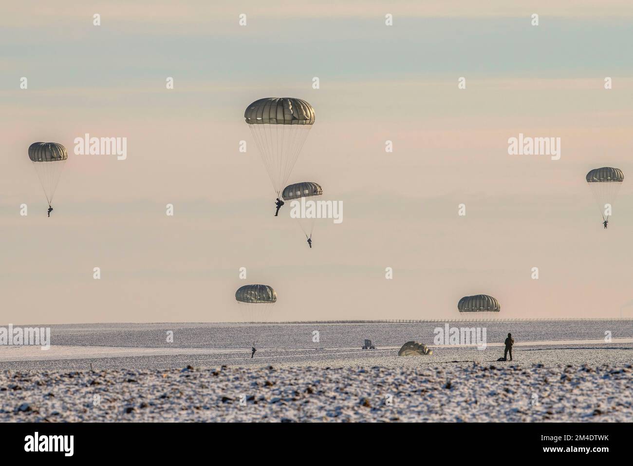 Fallschirmjäger landen in der Alzey Drop Zone nach einem Sprung von einer C-130 Hercules am 16. Dezember 2022. Das multinationale Unternehmen ermöglicht es den Dienstleistern, sich mit den Geräten der jeweils anderen zu vertraut zu machen. (USA Armeefoto von Volker Ramspott) Stockfoto
