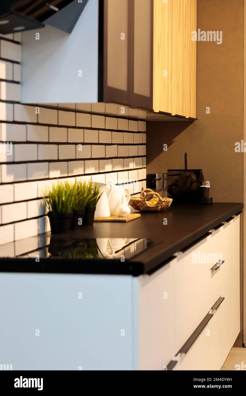 Modernes, stilvolles, kleines Küchenlayout. Küche mit schwarzer Arbeitsfläche und weißen Schränken. Selektiver Fokus. Stockfoto
