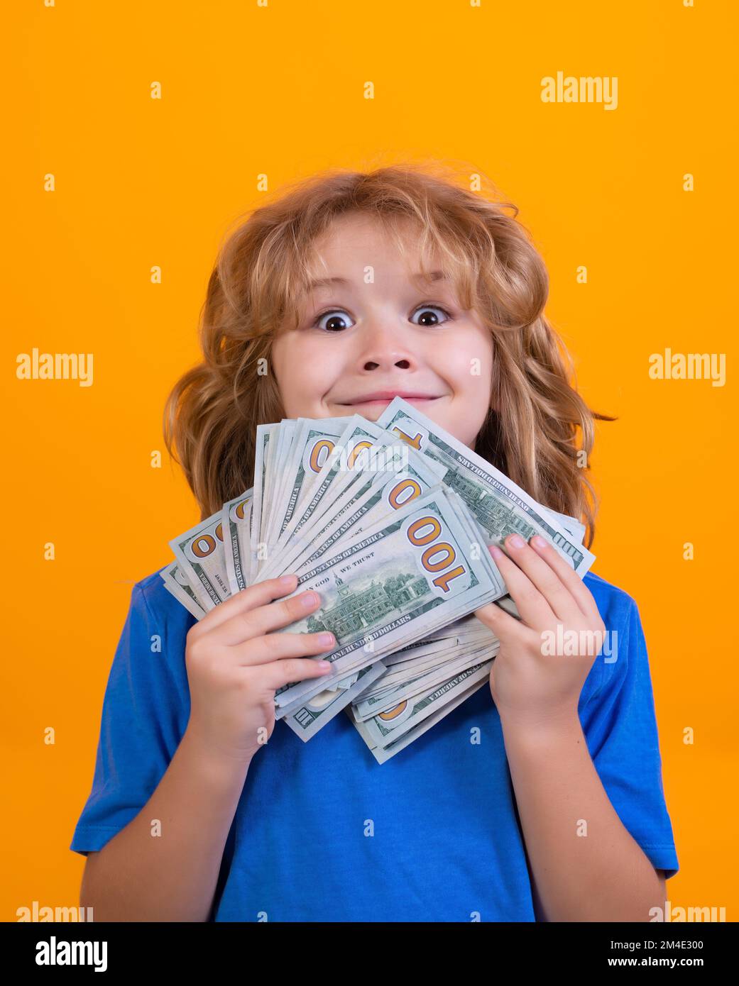 Ein Junge zeigt Dollarscheine, träumt von Reichen vor isoliertem Studiohintergrund. Stockfoto