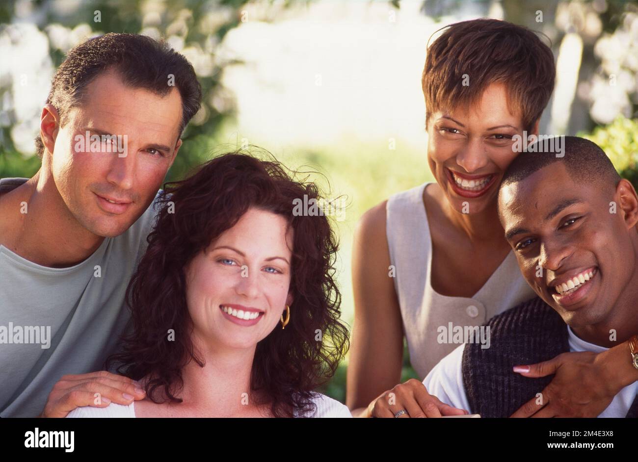 Zwei Paare, die für ein Kamerafoto posieren. Kaukasisches Paar und afroamerikanisches Paar, das lächelt Stockfoto