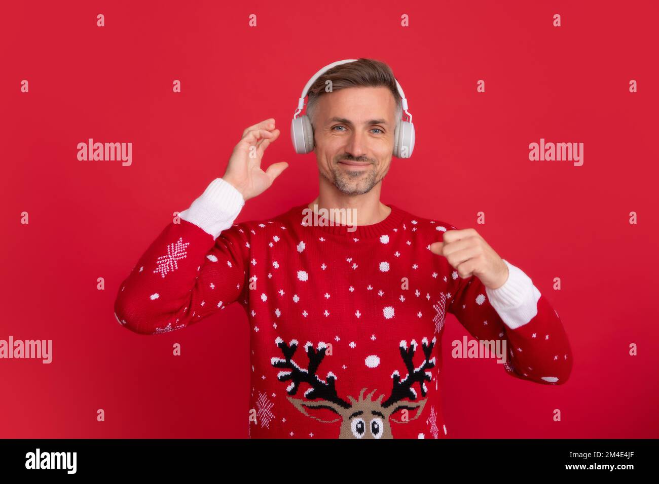 Weihnachtsmusik. Weihnachtsmann mit Kopfhörern. Porträt des weihnachtsmanns auf rotem Studiohintergrund. Stockfoto