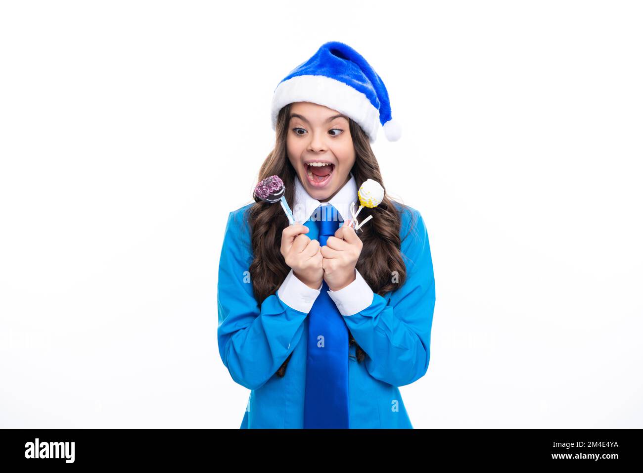 Aufgeregte Teenager halten weihnachtsbonbons Lollipop. Schönheitsmädchen zu weihnachten Neujahr isoliert im weißen Studiohintergrund. Teenager mit weihnachtsmann-Hut. Blau Stockfoto