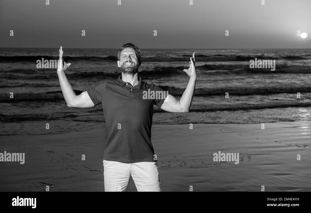 Glücklicher erfolgreicher Mann über dem Meer am Sonnenuntergang Sommerstrand, Erfolg Stockfoto