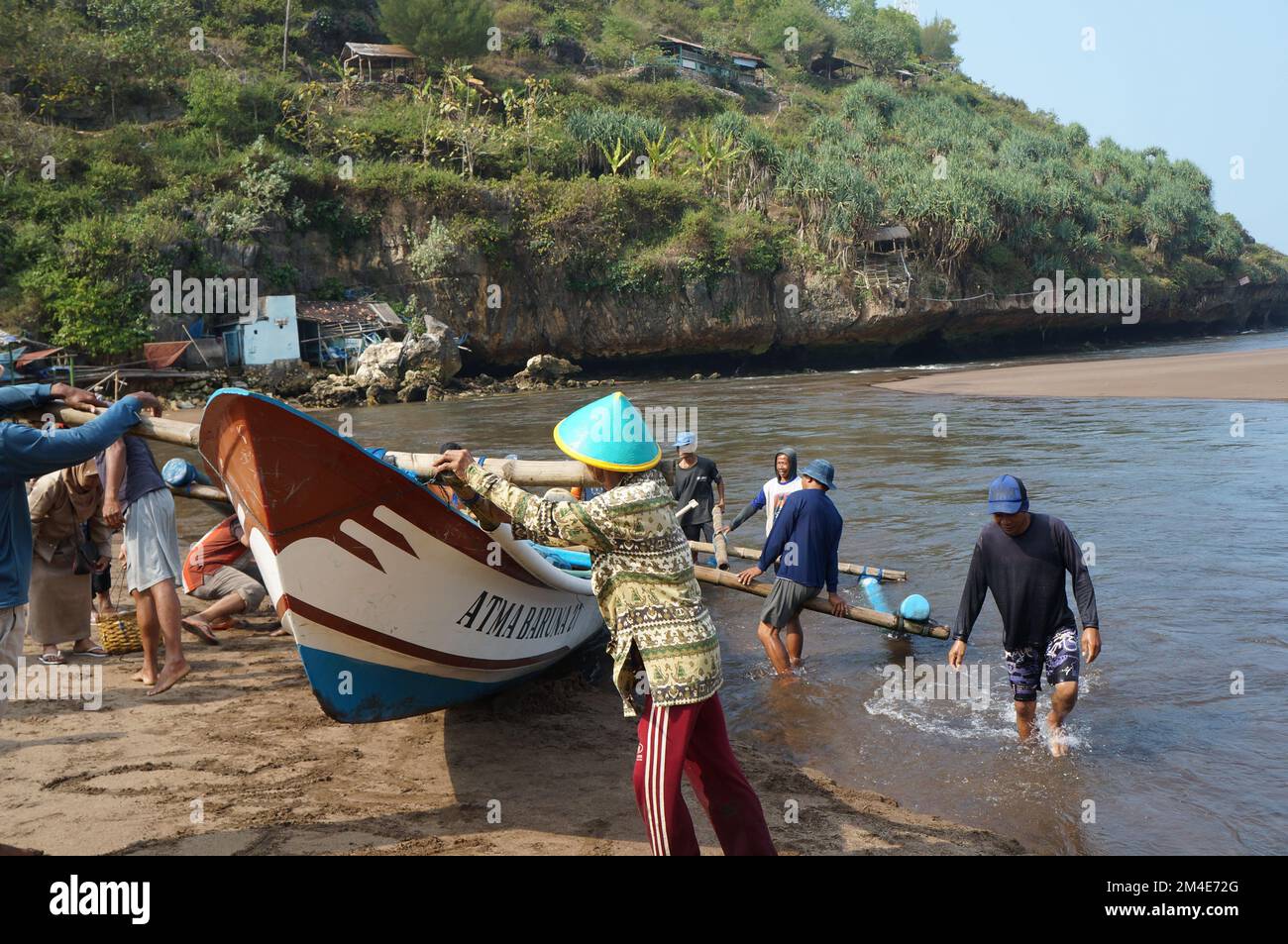Eine Gruppe traditioneller indonesischer Fischer hebt ein Boot am Strand von Yogyakarta, Indonesisch Stockfoto