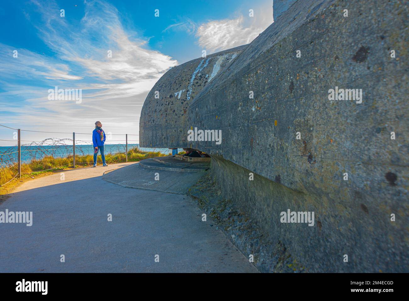 Eine alleinstehende Frau vor einem Bunker mit deutschen Waffen in Omaha Beach, Normandie, Frankreich Stockfoto