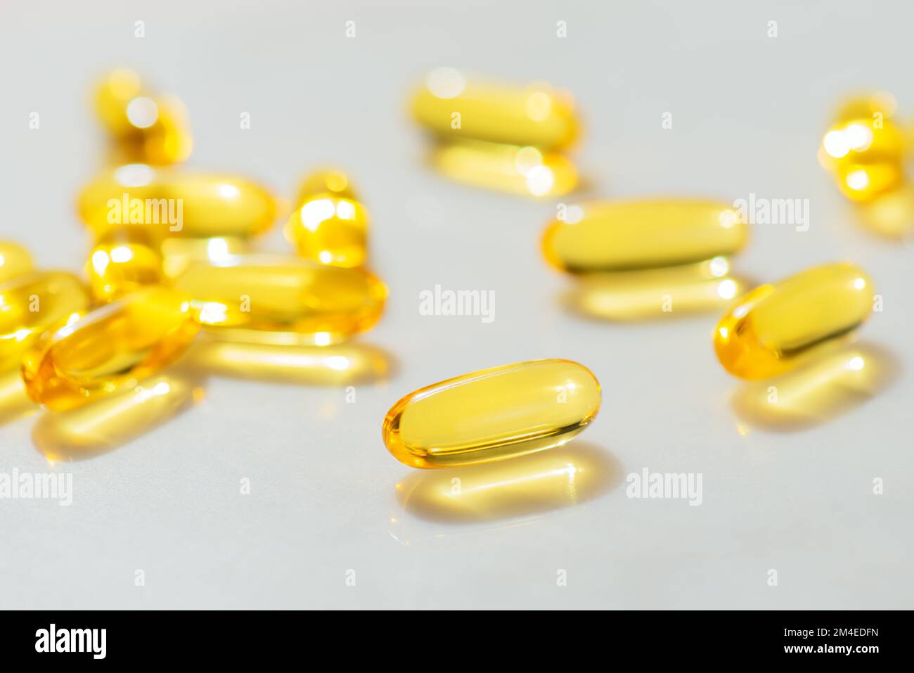 Fish Oil Omega 3 Kapseln fallen auf weißen Marmorhintergrund, Konzept der gesunden Ernährung, Krankheitsvorbeugung und Behandlung, Nahrungsergänzungsmittel Stockfoto