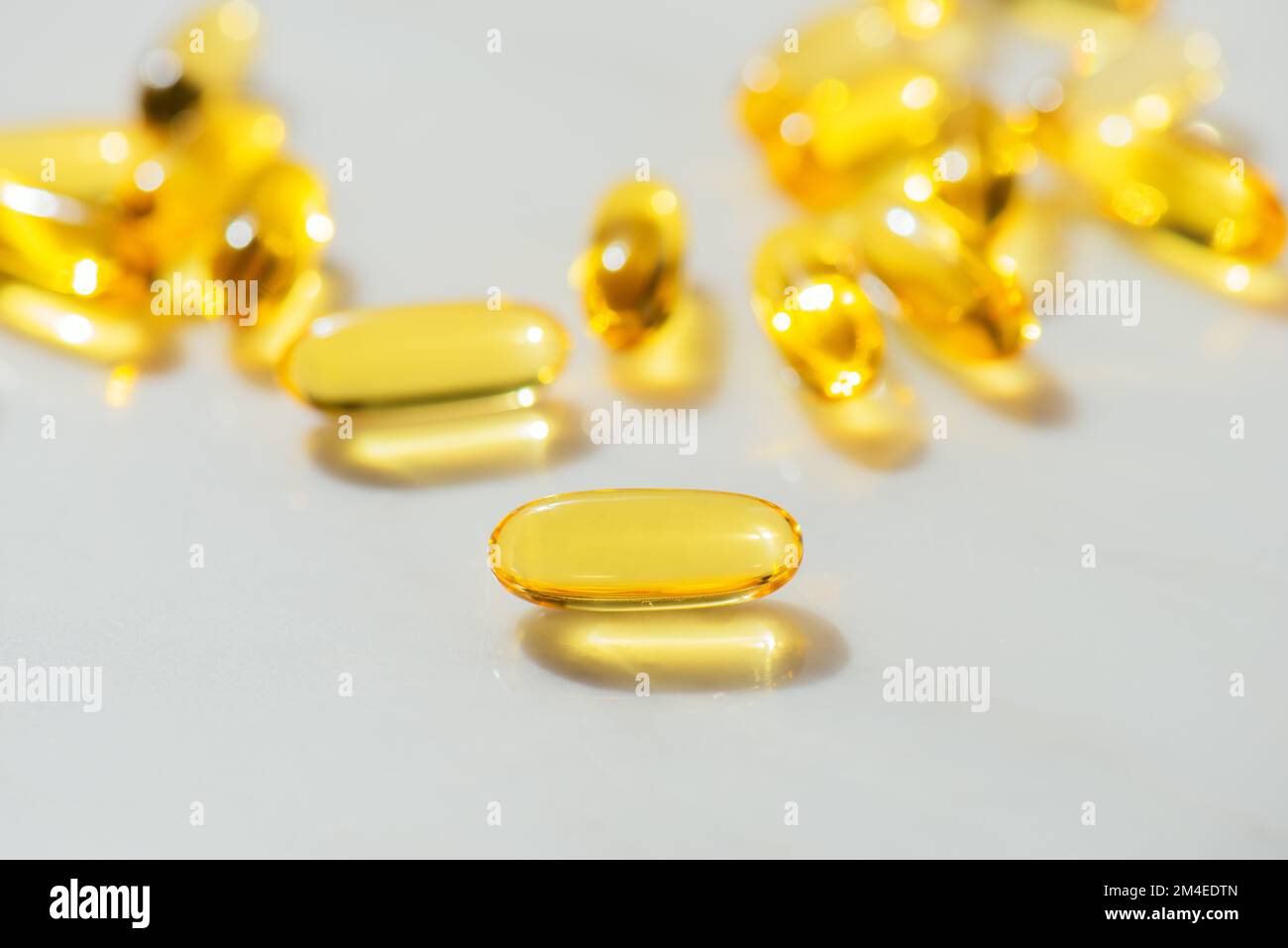 Fish Oil Omega 3 Kapseln fallen auf weißen Marmorhintergrund, Konzept der gesunden Ernährung, Krankheitsvorbeugung und Behandlung, Nahrungsergänzungsmittel Stockfoto