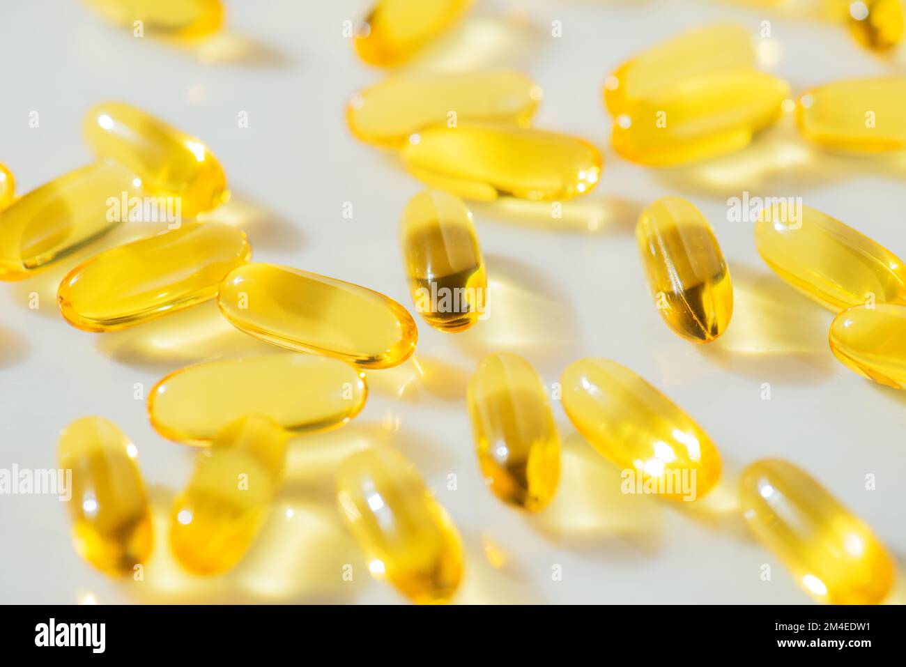 Fish Oil Omega 3 Kapseln fallen auf weißen Marmorhintergrund, Konzept der gesunden Ernährung, Krankheitsvorbeugung und Behandlung, Nahrungsergänzungsmittel Stockfoto