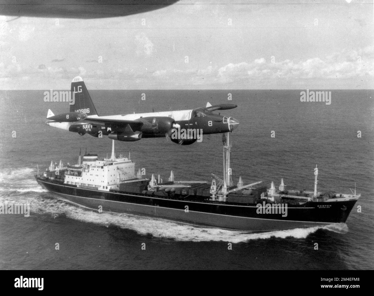 Ein US Navy P-2H-Neptun von VP-18, der über ein sowjetisches Frachtschiff fliegt, mit verpackten Ilyushin Il-28-Bombern an Deck während der Kubakrise Stockfoto