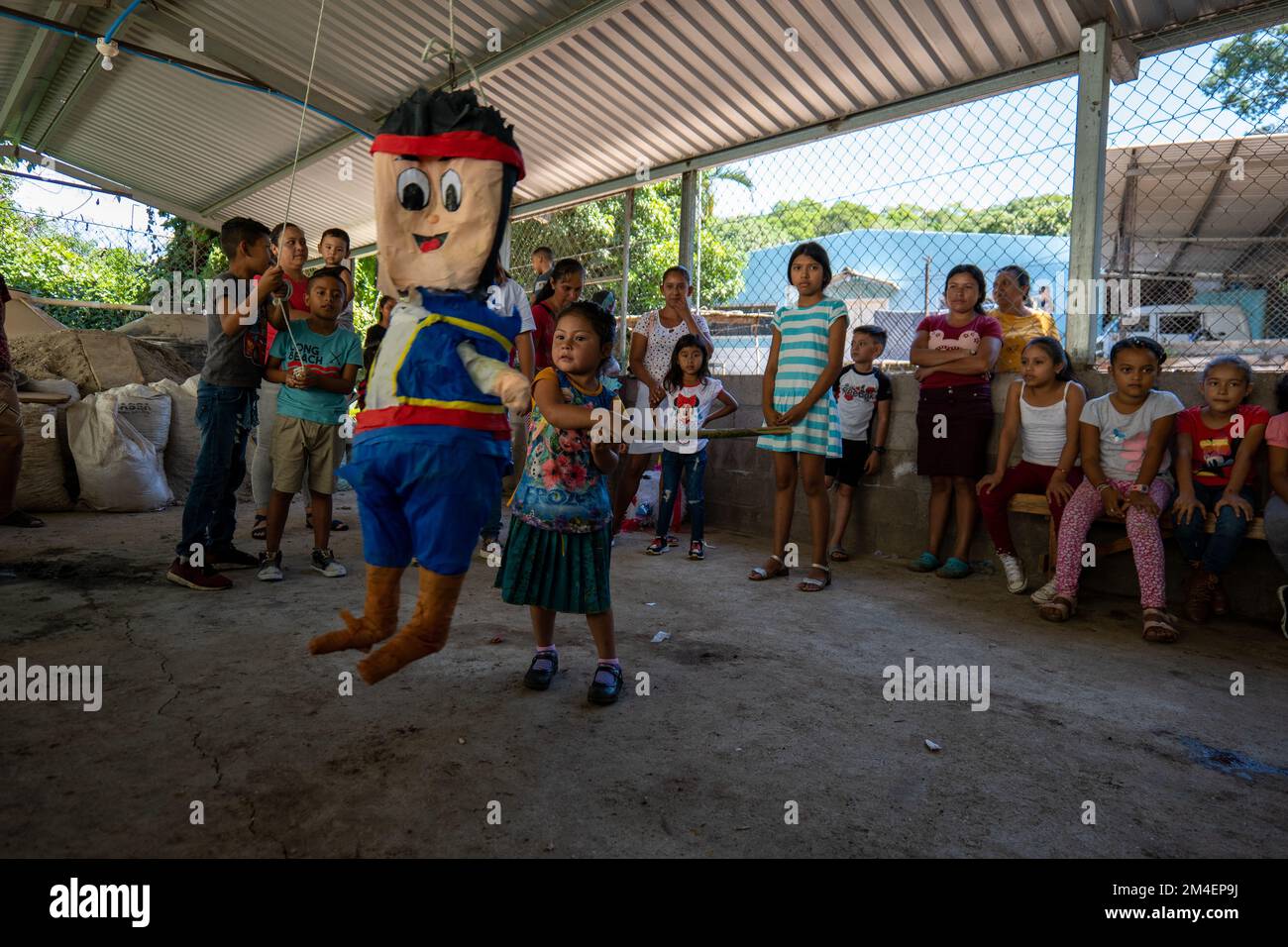 La Labor, La Libertad, Salvador - 27. Oktober 2022 - Little Brown Girl hält einen Stock, um die Piñata in der Mitte eines Circle Fulled wi zu schlagen und zu brechen Stockfoto