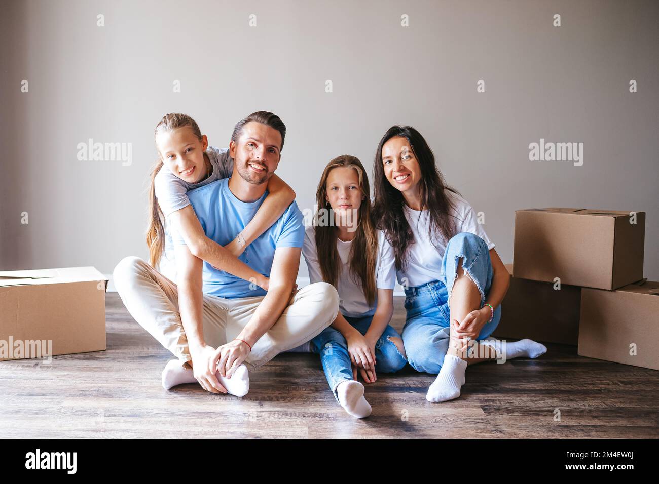 Glückliche Familie mit zwei Töchtern mit Pappkartons im neuen Haus am Umzugstag Stockfoto