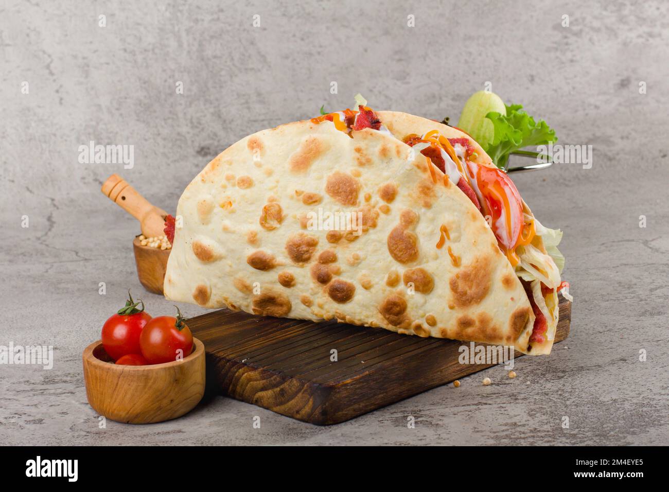 Mexikanische Tacos mit Rind-, Salat-, Tomaten- und Käsesauce auf rustikalem Holzbrett Stockfoto
