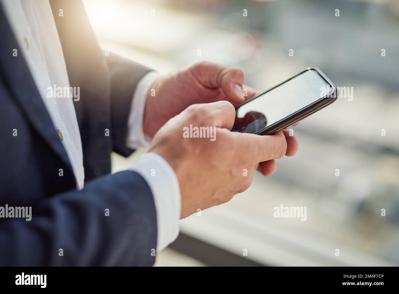 Bleiben Sie in der Nähe Ihrer Geschäftskontakte. Ein Geschäftsmann, der ein Mobiltelefon in einem modernen Büro benutzt. Stockfoto