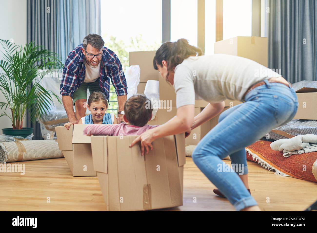 Der Übergang in ihr neues Zuhause wird ein Spaß. Eine glückliche Familie, die zusammen Spaß am Umzugstag hat. Stockfoto