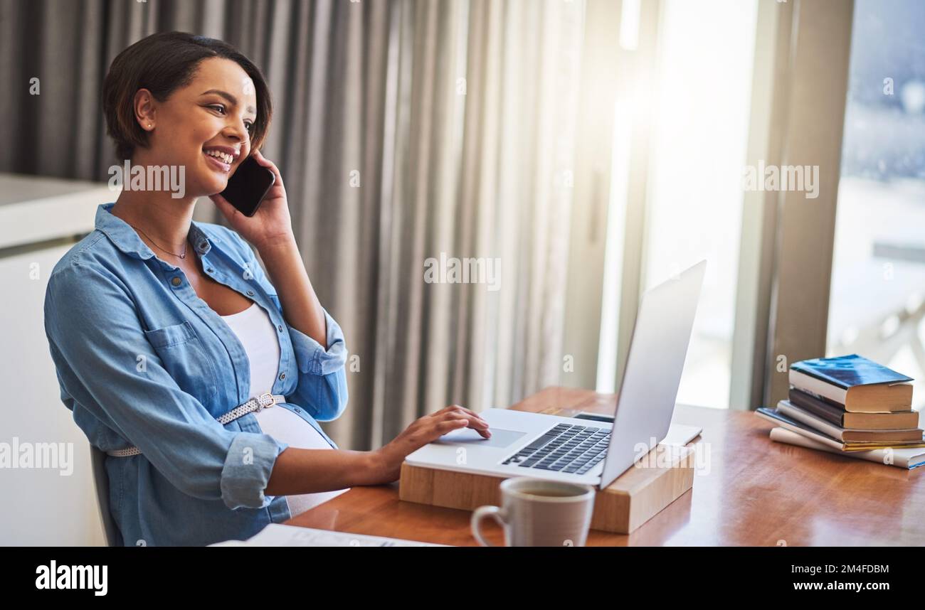 Im Mutterschaftsurlaub... oder nicht ganz. Eine schwangere junge Frau, die von zu Hause aus mit einem Laptop und Mobiltelefon arbeitet. Stockfoto
