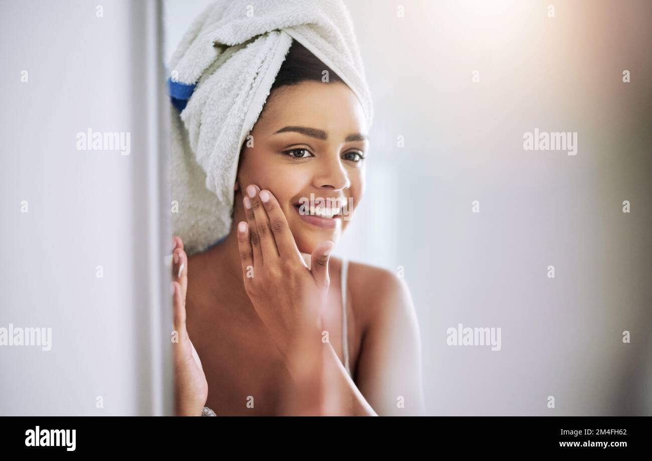 Diese Feuchtigkeitscreme wirkt auf jeden Fall Wunder für mich. Eine attraktive junge Frau, die sich im Bad Feuchtigkeitscreme ins Gesicht trägt. Stockfoto