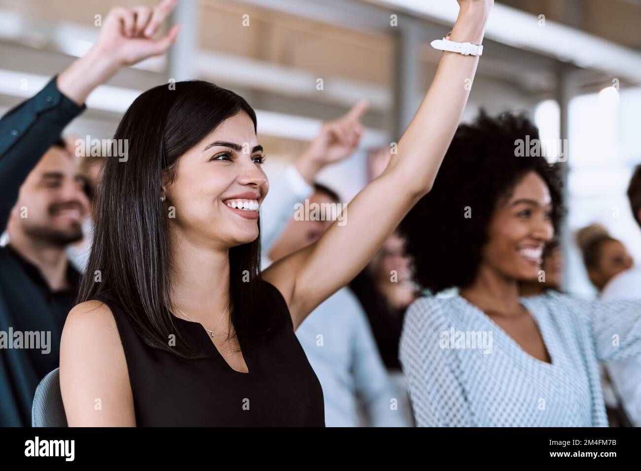 Wenn Sie Fragen stellen, wird die Zusammenarbeit bei der Konferenz verbessert. Eine Gruppe von Geschäftsleuten, die während einer die Hand heben, um Fragen zu stellen Stockfoto