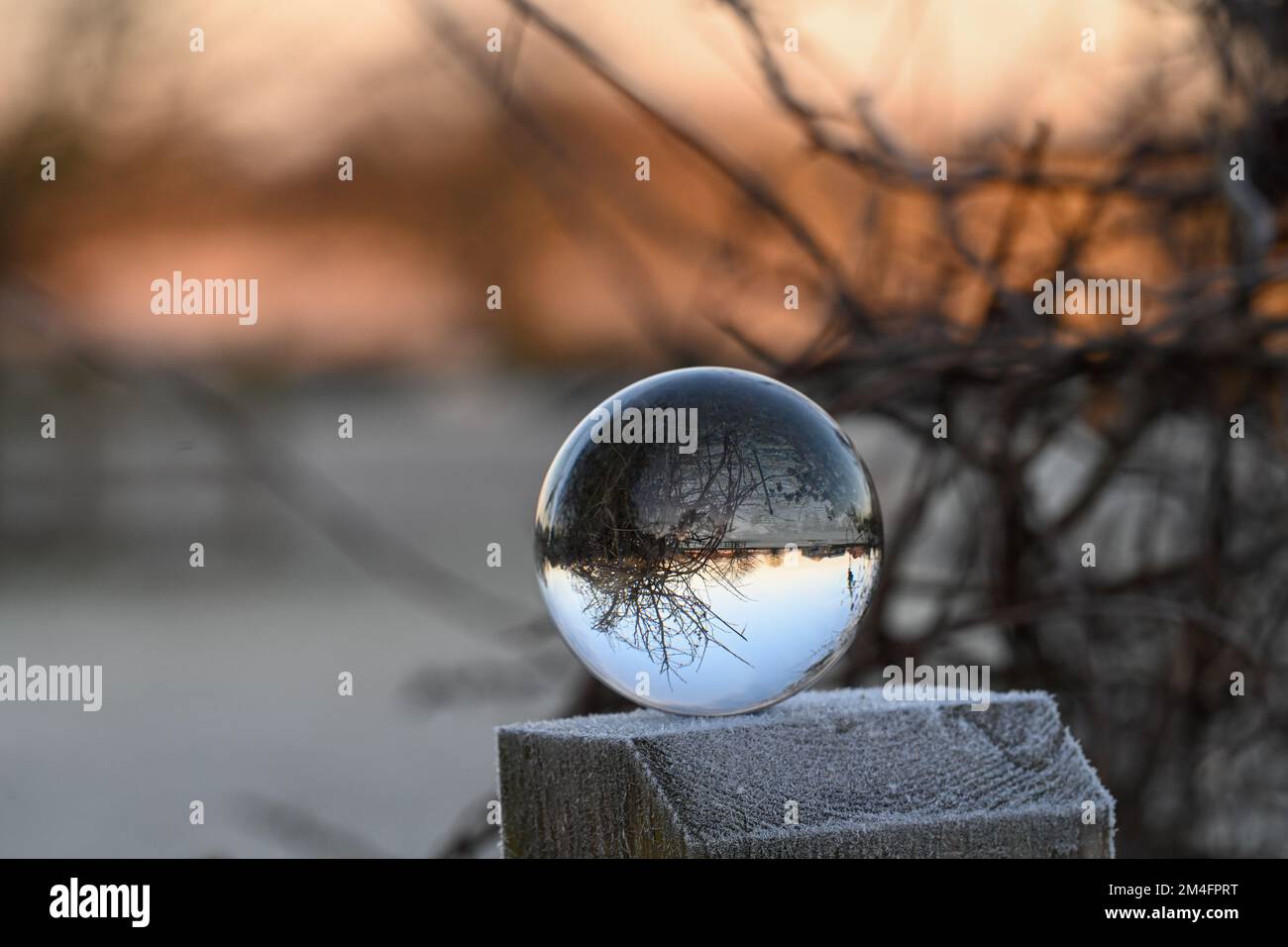 Ein frischer Blick auf den Winter am Morgen durch eine kristallklare Kristallkugel, eine umgedrehte Landschaft, die die Umgebung reflektiert Stockfoto