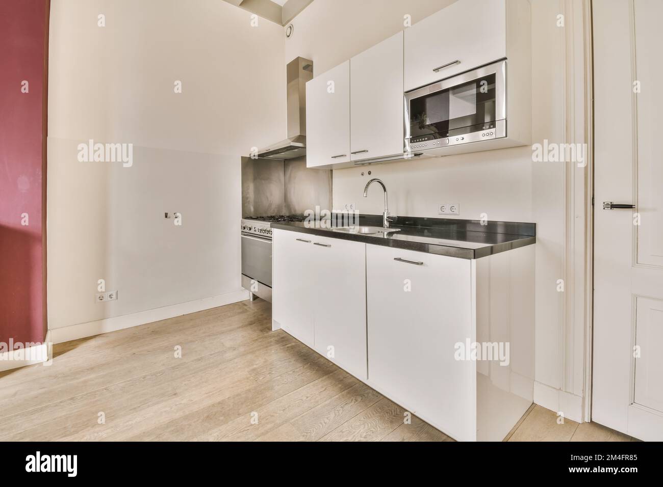 Ein Küchenbereich mit weißen Schränken und schwarzen Ablageflächen in diesem Zimmer ist sehr sauber, aber das ist es nicht Stockfoto