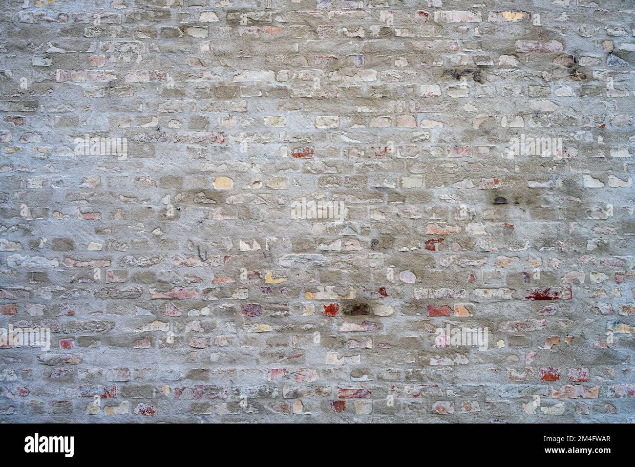 Hintergrund einer grauen Ziegelwand mit etwas Putz darauf Stockfoto