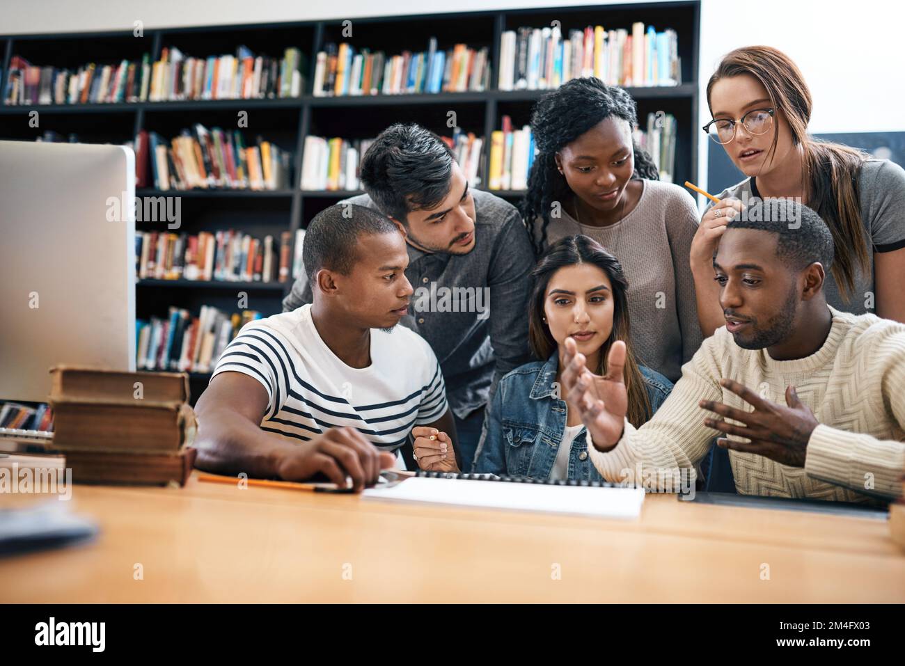 Planen und planen Sie den Weg zu großartigen Ergebnissen. Eine Gruppe junger Studenten, die zusammen an einem Auftrag in einer Collegebibliothek arbeiten. Stockfoto