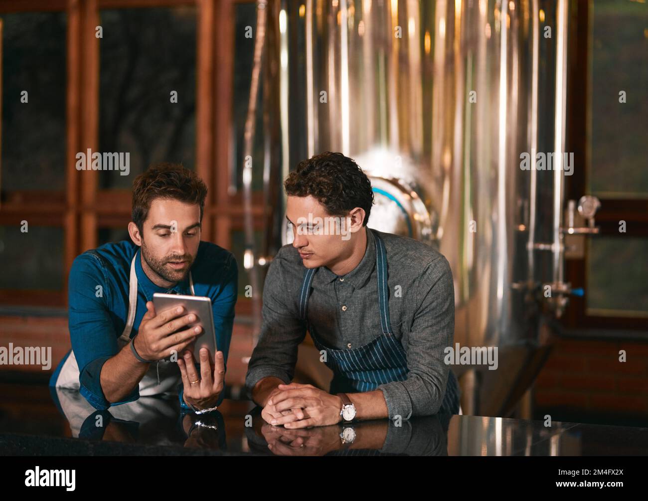 So sehen unsere Zahlen derzeit aus. Zwei Geschäftsleute, die tagsüber in einer Bierbrauerei zusammen auf einem Handy surfen. Stockfoto