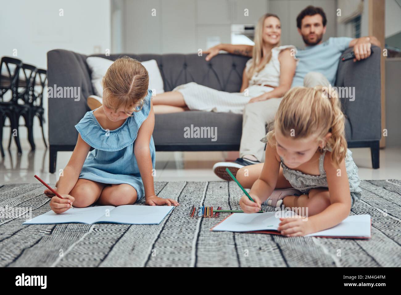 Wohnzimmer, Eltern entspannen sich und Kinder malen Bücher auf dem Boden in ihrem modernen Zuhause. Mutter, Vater und Mädchen sitzen in der Lounge Stockfoto