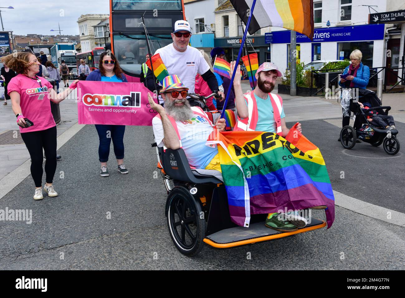 Teilnehmer, die in einer Chat Van Raam Electric Rikscha in der farbenfrohen Cornwall Prides Pride Parade im Zentrum von Newquay in Großbritannien reiten. Stockfoto