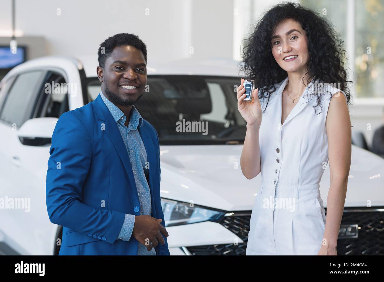 Schwarzhaarige, weibliche Kundin, die Schlüssel hat, kauft im Automobil-Salon. Geschäftsfrau sieht zufrieden und begeistert aus Stockfoto