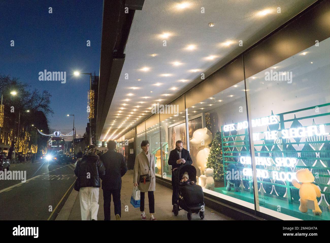 London, UK, 20. Dezember 2022: Besucher genießen mildes und trockenes Wetter vor Weihnachten auf der King's Road in Chelsea. Aufwändige Weihnachtslichter und Dekorationen heben sich in der Dämmerung hervor, aber an einigen Tagen wurde der Fußabdruck durch Zugstreiks verringert. Anna Watson/Alamy Live News Stockfoto