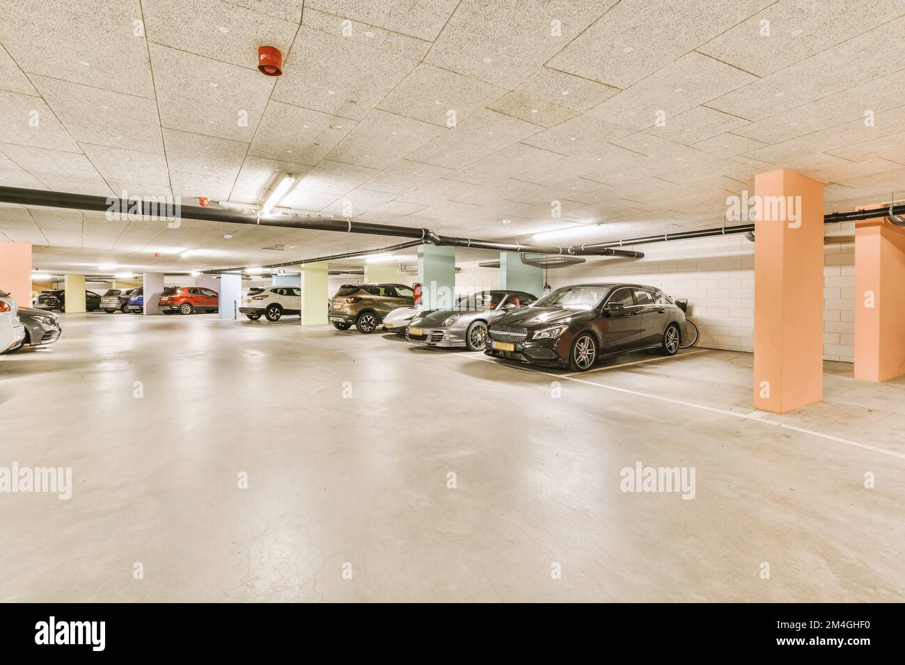 Mehrere Autos parkten auf einem Parkplatz mit orangefarbener und grüner Farbe an den Wänden, zusammen mit weißem Fußboden Stockfoto