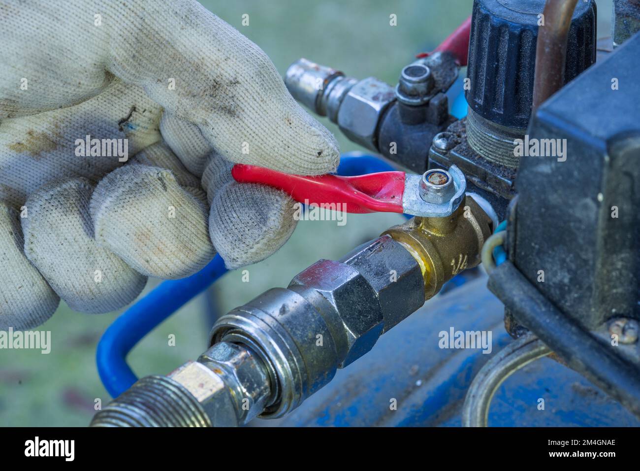 Techniker hält das Steuerventil des Luftkompressors mit der Hand, rotes Ventil. Stockfoto