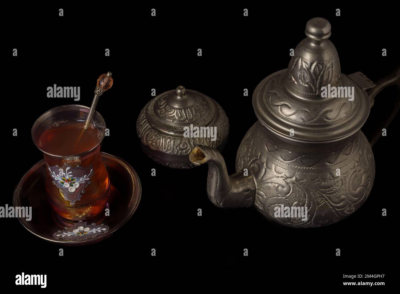 Teetasse mit Teekanne und Zuckerschale aus Metall, isoliert auf schwarzem Hintergrund Stockfoto