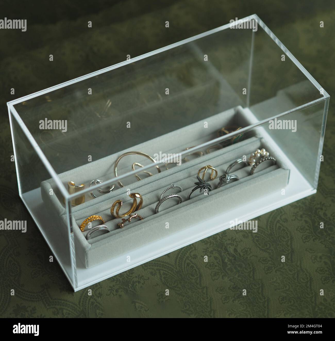 Die Schmuckkiste aus Glas mit goldenen und silbernen Ringen und Ohrringen, Nahaufnahme Stockfoto