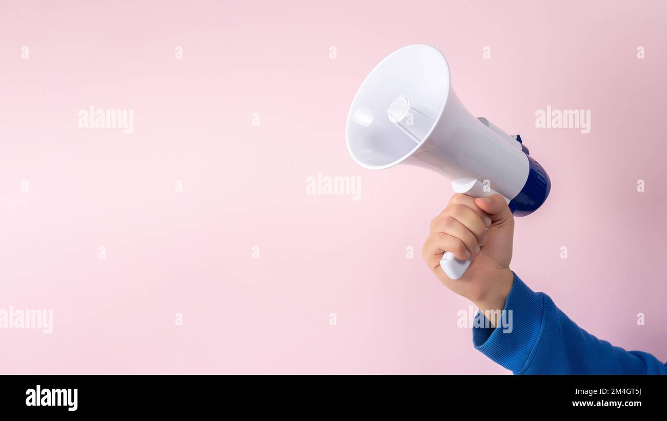 Männerhand mit Megafon auf pinkfarbenem Hintergrund. Minimaler Werbehintergrund. Stockfoto
