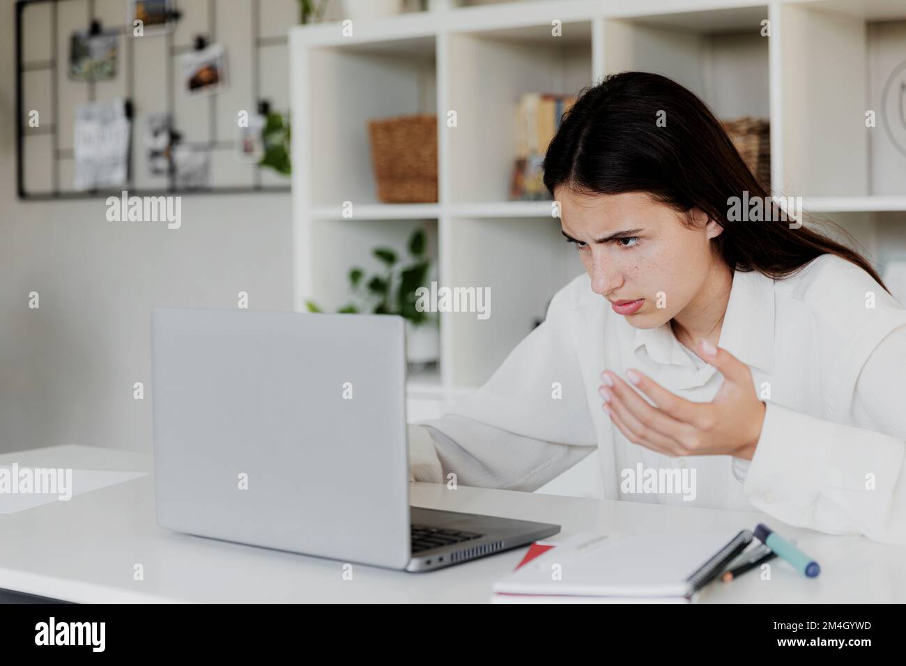 Verärgerte junge Frau im Heimbüro arbeitet online am Computer und hat Probleme mit dem Gerät. Unzufriedene verwirrte Frau, die mit Laptop-Problemen in Bedrängnis ist, verzweifelt aussieht, Kreditkartenprobleme beim Einkaufen Stockfoto