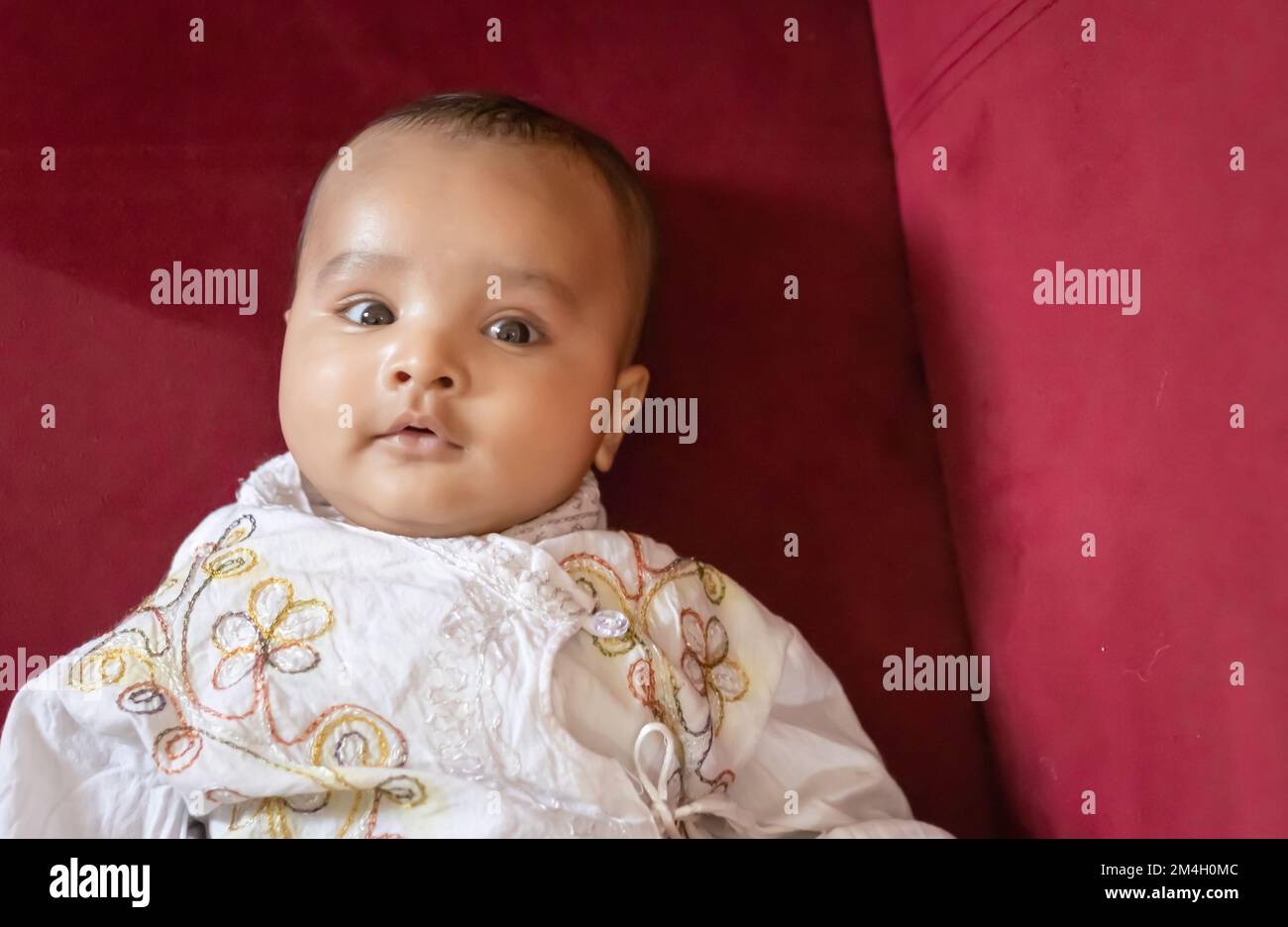 Ein Junge im traditionellen indischen Outfit liegt auf dem Sofa süßer Gesichtsausdruck im Haus Stockfoto
