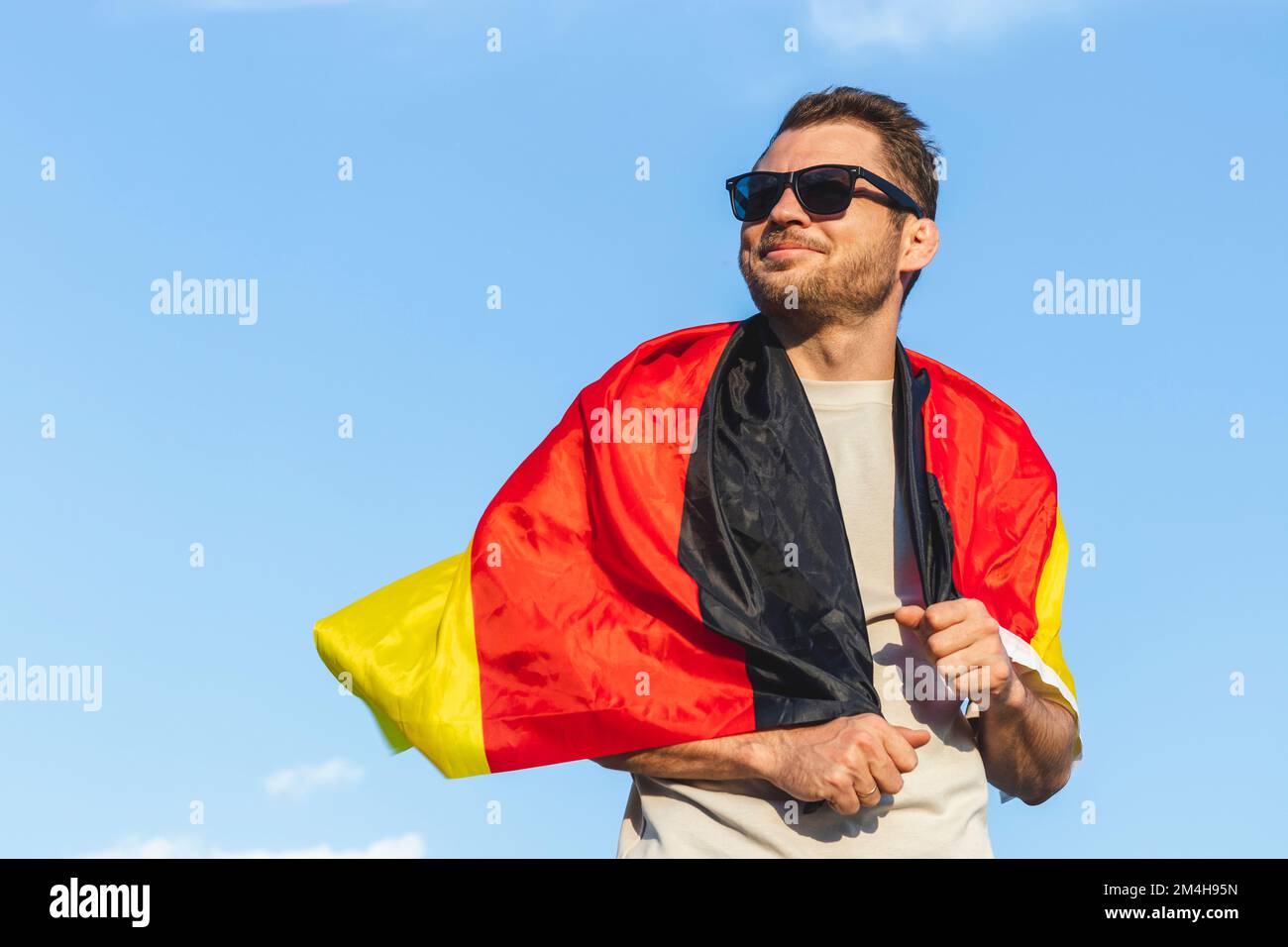 Flagge Deutschlands auf den Schultern des Mannes in Sonnenbrille gegen  blauen Himmel Stockfotografie - Alamy