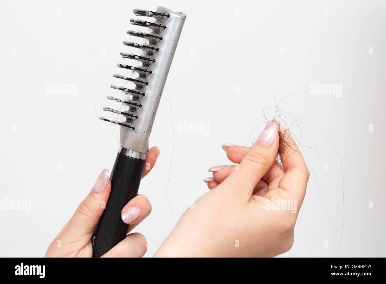 Nahaufnahme weiblicher Hände mit Kamm und Haarsträhne. Trichotillomanie und Haarausfall Stockfoto