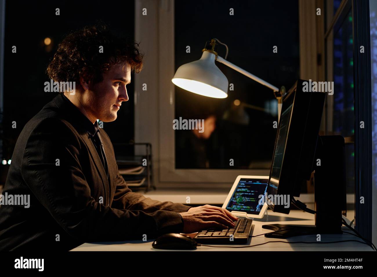 Junger Programmierer, der Codes auf dem Computer schreibt, um neue Software zu entwickeln, er arbeitet Überstunden im Büro Stockfoto