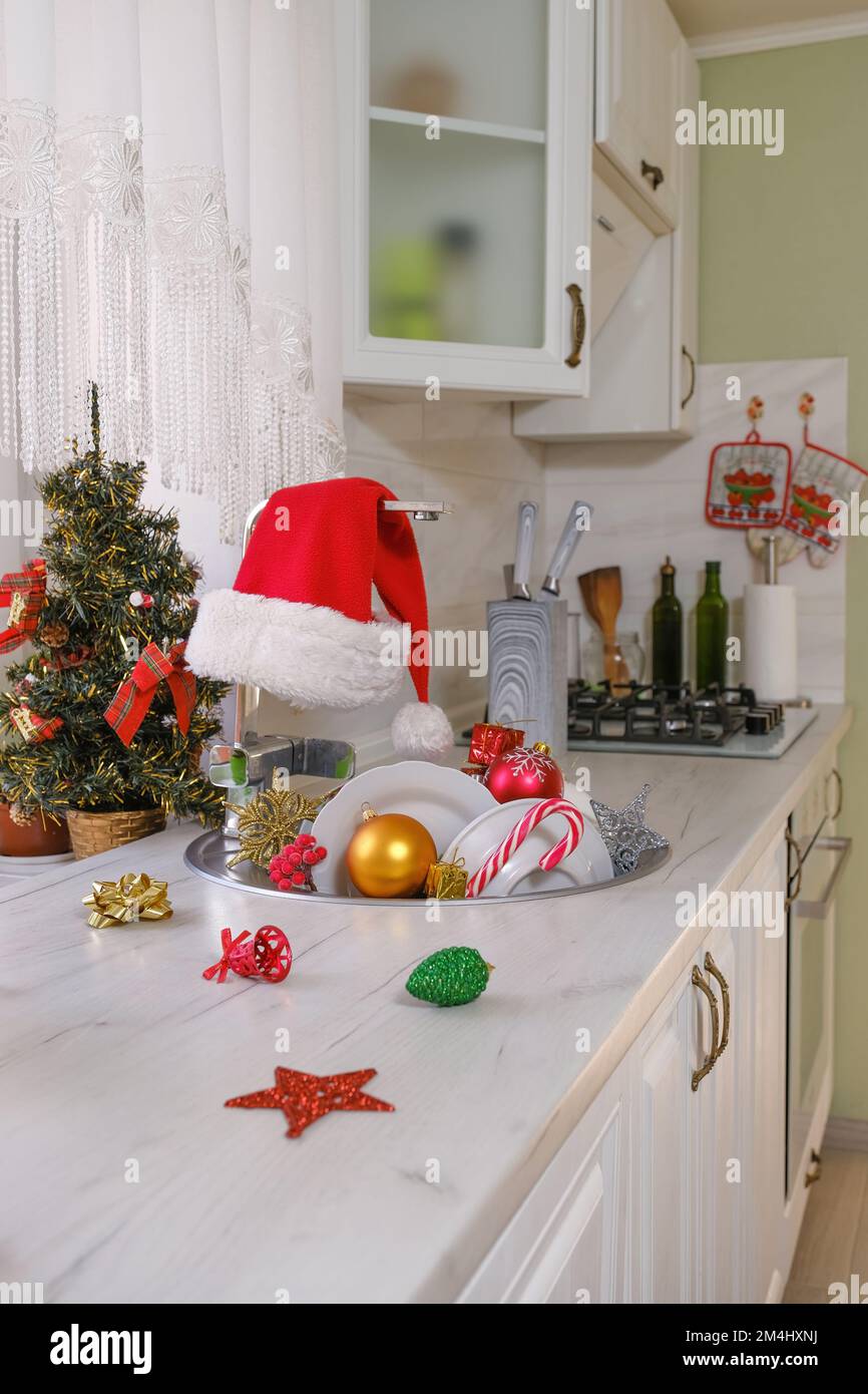 Weihnachtsspielzeug und ungewaschene Geschirr in der Küchenspüle Stockfoto