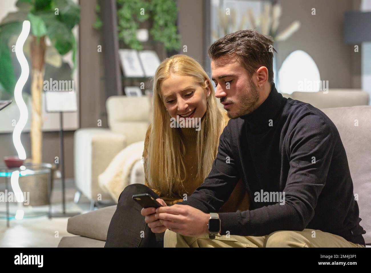 Ein paar Freunde, die ein glückliches Smartphone sehen. Teilen von