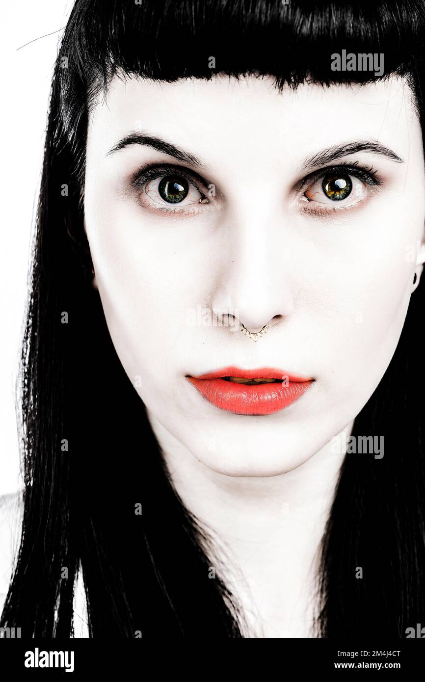 Porträtieren Sie eine junge Frau mit langen schwarzen Haaren und roten Lippen, ein gotisches Mädchen Stockfoto
