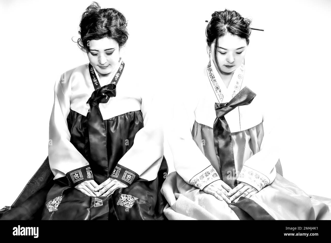 Zwei sitzende Frauen im traditionellen koreanischen Kostüm verbeugen sich mit den Köpfen, koreanische Geschwister in hanbok, Schwestern, Korea, Schwarzweißfoto Stockfoto